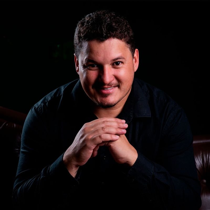 Menezes, gestor de tráfego pago de Meta Ads, Google Ads e TikTok Ads, sorrindo com as mãos entrelaçadas